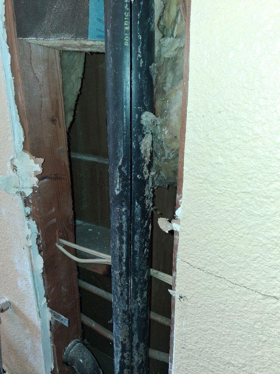 Cracked DWV pipe at the open laundry-room wall.